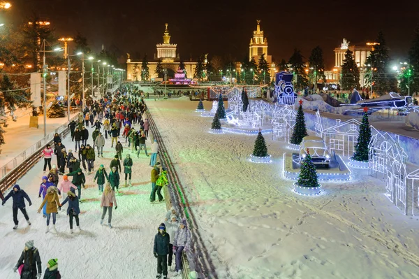 People skating near decorations and illuminations at winter nigh — Stock Photo, Image