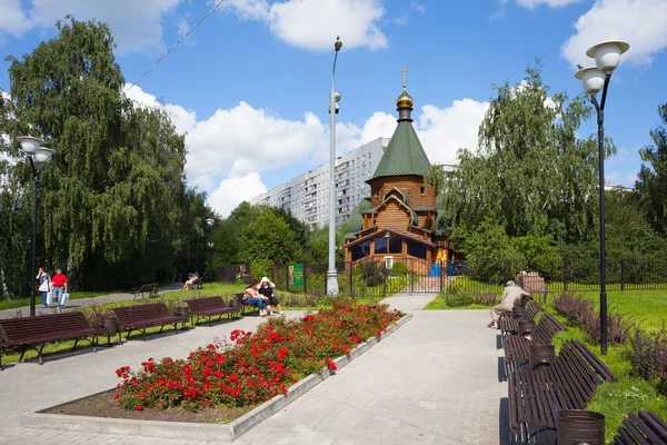 People resting on benches near a wooden cathedral — Stock Photo, Image