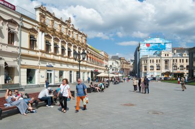 People walking and sitting on benches on Kuznetsky Most Street