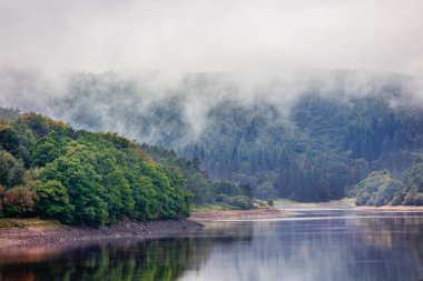 Ladybower 'ın Peak District Ulusal Parkı' ndaki rezervuarından puslu, sisli manzara manzaraları, İngiltere 'nin sisli havası, rezervuarı çevreleyen ormanlık alandan yükseliyor..