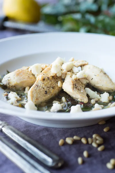 Pollo al limone con bietola saltata e pinoli Immagine Stock