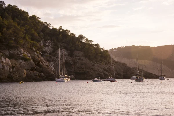 Bateaux au coucher du soleil dans la petite baie de Cala Benirras, île d'Ibiza . — Photo