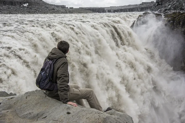 Junger Mann am Rande des Abgrunds beim Betrachten eines Detafoss-Wasserfalls in Island. — Stockfoto