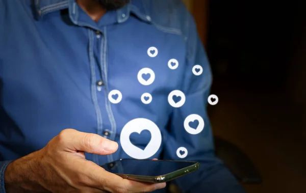 Hombre usando un smartphone con iconos del corazón. —  Fotos de Stock