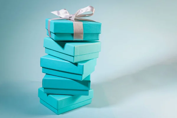 Stack of turquoise blue boxes, one tied with white silk ribbon