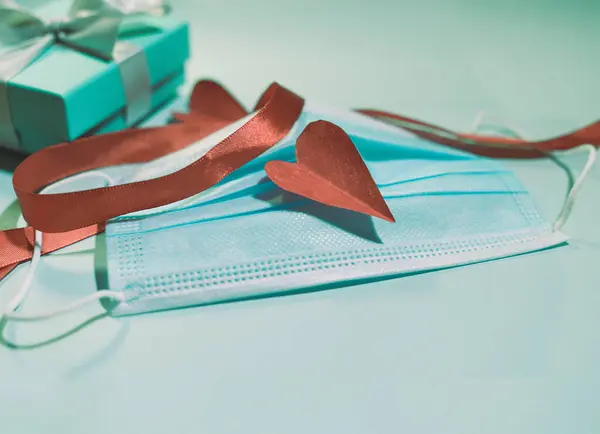 Corazón hecho a mano de papel encima de una mascarilla. Concepto de San Valentín. — Foto de Stock