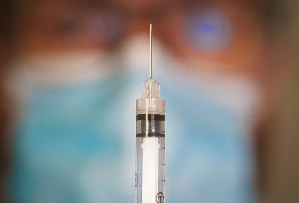 Close-up of hypodermic syringe with blurred doctor on the background. — Stock Photo, Image