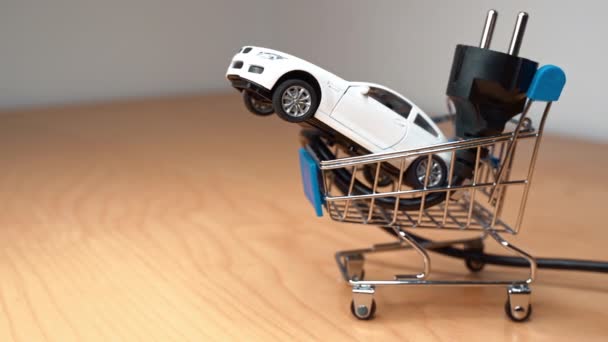 Játék autó és elektromos dugó egy kis bevásárlókocsiban — Stock videók