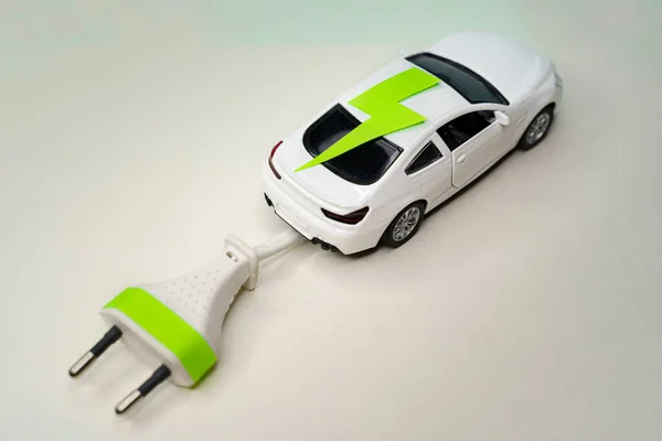 Speelgoedwagen en elektrische stekker. Elektrische auto en groene auto concept Stockafbeelding
