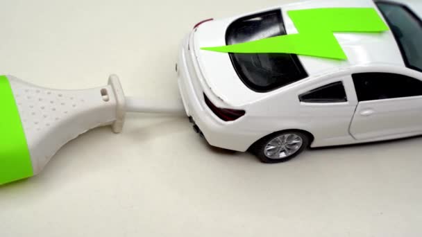Carro de brinquedo e tomada elétrica. Carro elétrico e conceito de carro verde — Vídeo de Stock