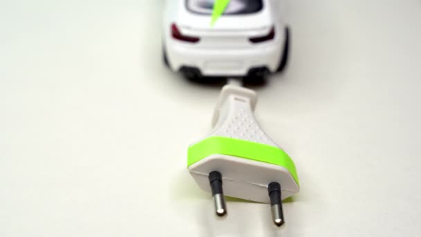 おもちゃの車と電気プラグ。電気自動車とグリーンカーのコンセプト — ストック動画