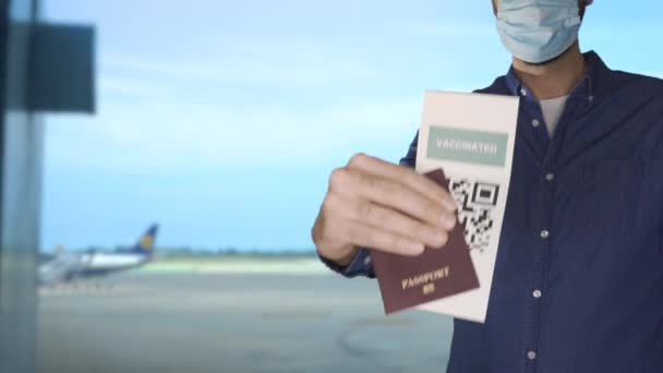 Unbekannter trägt Gesichtsmaske und hält Reisepass und grünen Ausweis in der Hand, QR-Code für Impfpass. — Stockvideo