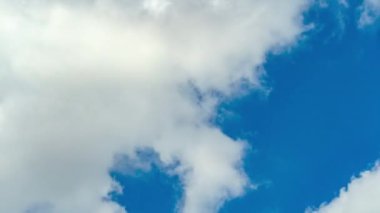 Mavi gökyüzü ve beyaz bulutların hareket ettiği bir zaman aralığının yakın görüntüsü.