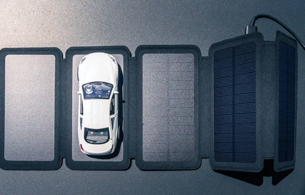 Mașină de jucărie deasupra unui panou solar. Mașină electrică alimentată cu energie solară și concept de încărcare . — Fotografie, imagine de stoc