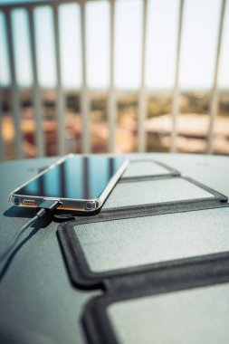 Evden akıllı bir telefonu taşınabilir güneş paneli şarj cihazıyla şarj etmek.