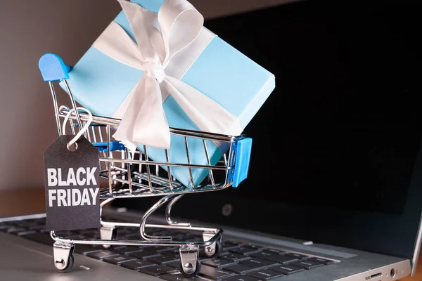 Small shopping cart with a gift inside and a Black Friday tag — Stock Photo, Image