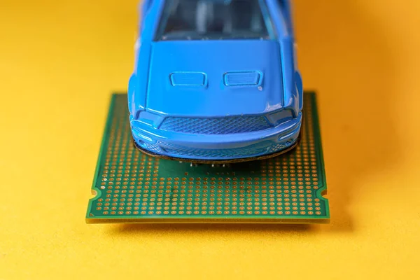 Close-up weergave van een blauwe speelgoedauto bovenop een microprocessor. — Stockfoto