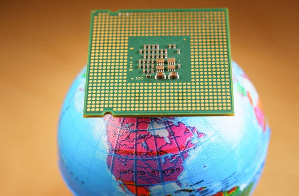 Foco seletivo de uma CPU no topo de um globo mundial contra um fundo laranja — Fotografia de Stock