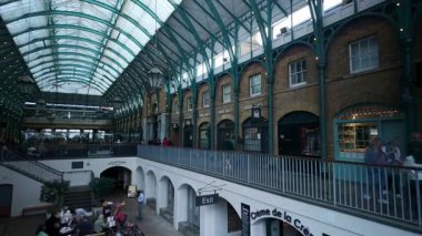 Londra, İngiltere. 27 Eylül 2025, Timelapse Londra, İngiltere 'deki tarihi Covent Garden pazarından geçen turist ve müşterileri gösteriyor.