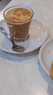 Tipik bir İspanyol kahvaltısının yakın görüntüsü şeker serpiştirilmiş lezzetli kızarmış churros ve bir bardak sütlü sıcak kahve, tatlı ve lezzetli bir yemek.