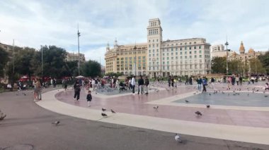 Barselona, İspanya. 1 Kasım 2025: Barselona 'nın en önemli simgelerinden biri olan ve Barselona' nın kalbinde canlı bir merkez olan ünlü Placa de Catalunya 'da, turistler ve yerliler arasında uçan ve yürüyen büyük bir güvercin sürüsü.