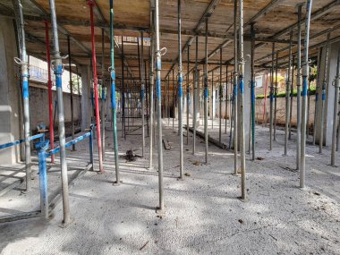 Yeni bina inşaatı, bir konut veya ticari projenin ilk aşamalarını temsil eden beton bir levha için iskele desteği ve biçimlendirme gösteriyor.