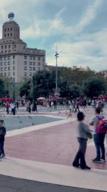 Barselona, İspanya. 1 Kasım 2025, Dinamik zaman çizelgesi İspanya 'nın Barcelona şehrinin göbeğindeki ikonik Placa de Catalunya' da hareket eden insan ve güvercin sürülerini gösteriyor.