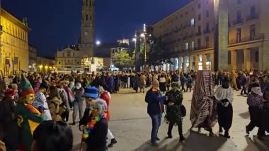 Zaragoza, İspanya. 28 Şubat 2025, İspanya 'nın Zaragoza kentindeki karnaval finali için Plaza del Pilar' da düzenlenen gece geçit töreninde renkli kostümler giyen insanlar dans ediyor ve kutlama yapıyorlar.