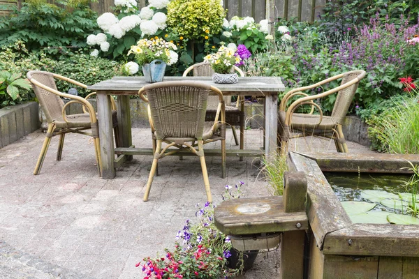 Wooden table and chairs in a ornamental garden — Stock Photo, Image