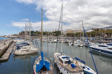 Yüzen jetleri ve demirli yelkenli gemileri olan Funchal marinası.