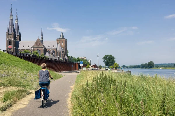 Hollanda köyü Cuijk yakınlarında Meuse nehri boyunca bisiklet süren bir kadın. — Stok fotoğraf