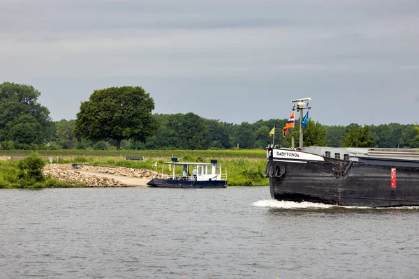 Small ferry crossing Dutch river Meuse waiting for cargo ship — Stock Photo, Image