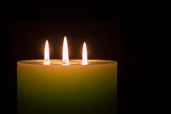 Kerze mit drei Flammen auf schwarzem Hintergrund — Stockfoto