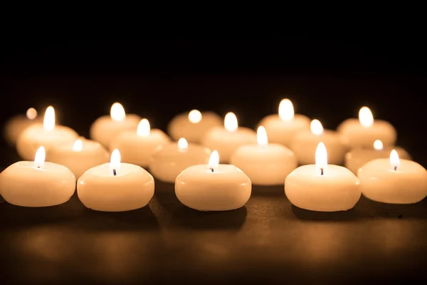 Several white candles with selective focus at a black background — Stock Photo, Image