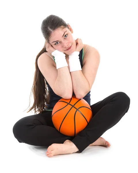 Mulher bonita em roupas esportivas sentado no chão com uma bola de basquete — Fotografia de Stock