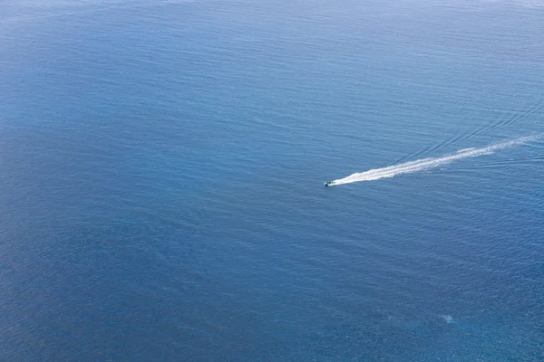 Вид с воздуха на небольшой корабль, плывущий по голубому океану — стоковое фото