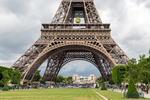 Туристы возле Эйфелевой башни с большим теннисным мячом Roland Garros в Париже, Франция — стоковое фото