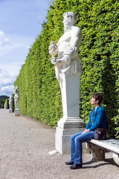 Mulheres sentadas ao lado de estátua ornamental no jardim Palace Versailles, Paris — Fotografia de Stock