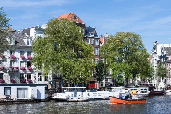 Small boat with relaxing people in Amsterdam canal — Stock Photo, Image