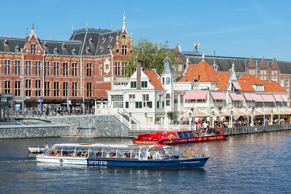 Motorbåt med turister i Amsterdam framför centralstationen — Stockfoto