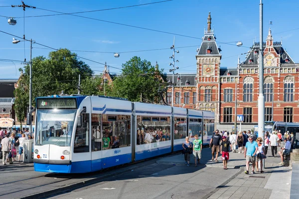 Туристы, идущие рядом с трамваем в Амстердаме — стоковое фото