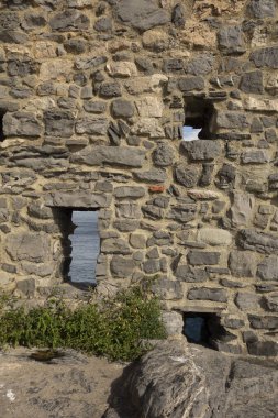 Deniz manzaralı boşlukları olan taş duvar.