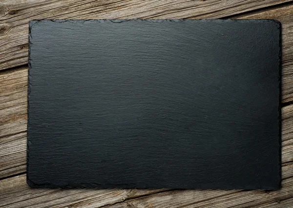 Slate over old wooden background — Stock Photo, Image