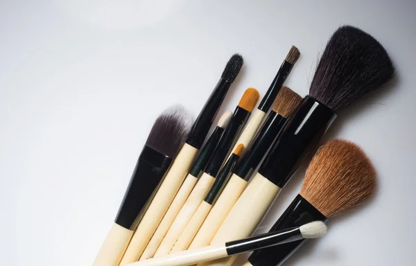 Bunch of make-up brushes lying randomly on white background. — Stock Photo, Image