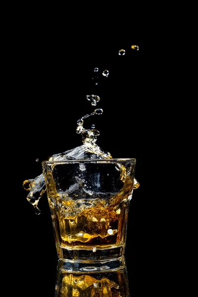Respingo de whisky em vidro isolado em fundo preto. — Fotografia de Stock