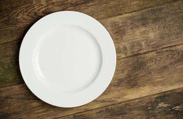 Empty white plate on rustic wooden background — Stock Photo, Image