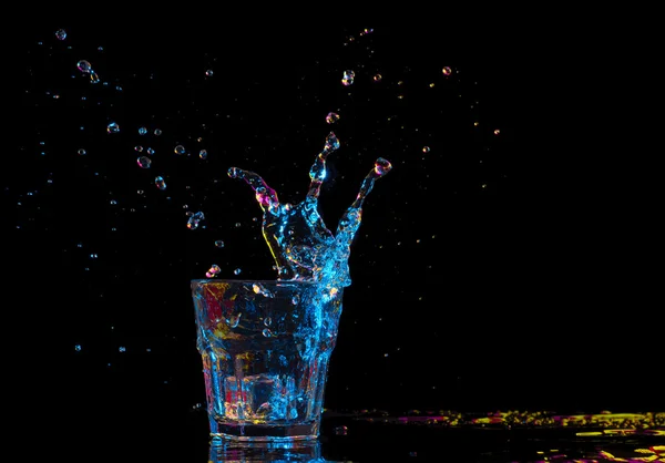 Cocktail in glass with splashes on dark background. Party club entertainment. Mixed light. — Stock Photo, Image