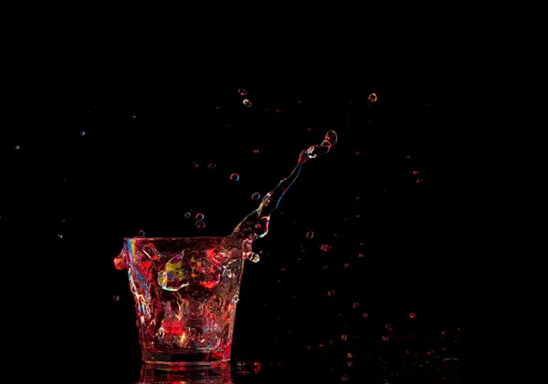 Bright cocktail in glass and splashing water on dark background — Stock Photo, Image