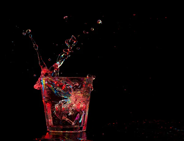 Cóctel en vaso con salpicaduras sobre fondo oscuro. Entretenimiento de club fiesta. Luz mixta. — Foto de Stock