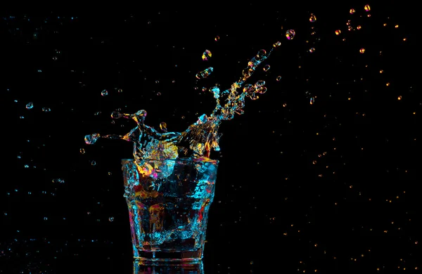 Cóctel en vaso con salpicaduras sobre fondo oscuro. Entretenimiento de club fiesta. Luz mixta. — Foto de Stock